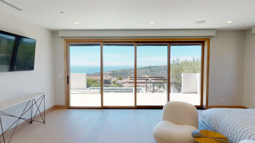 Interior view showcasing large sliding patio doors with a stunning coastal and hillside view, blending indoor comfort with outdoor beauty.