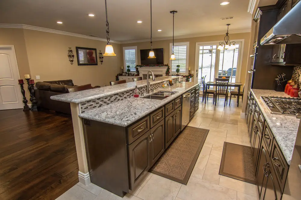 Spacious open concept kitchen with granite countertops, dark wood cabinets, and direct views into the living and dining areas.