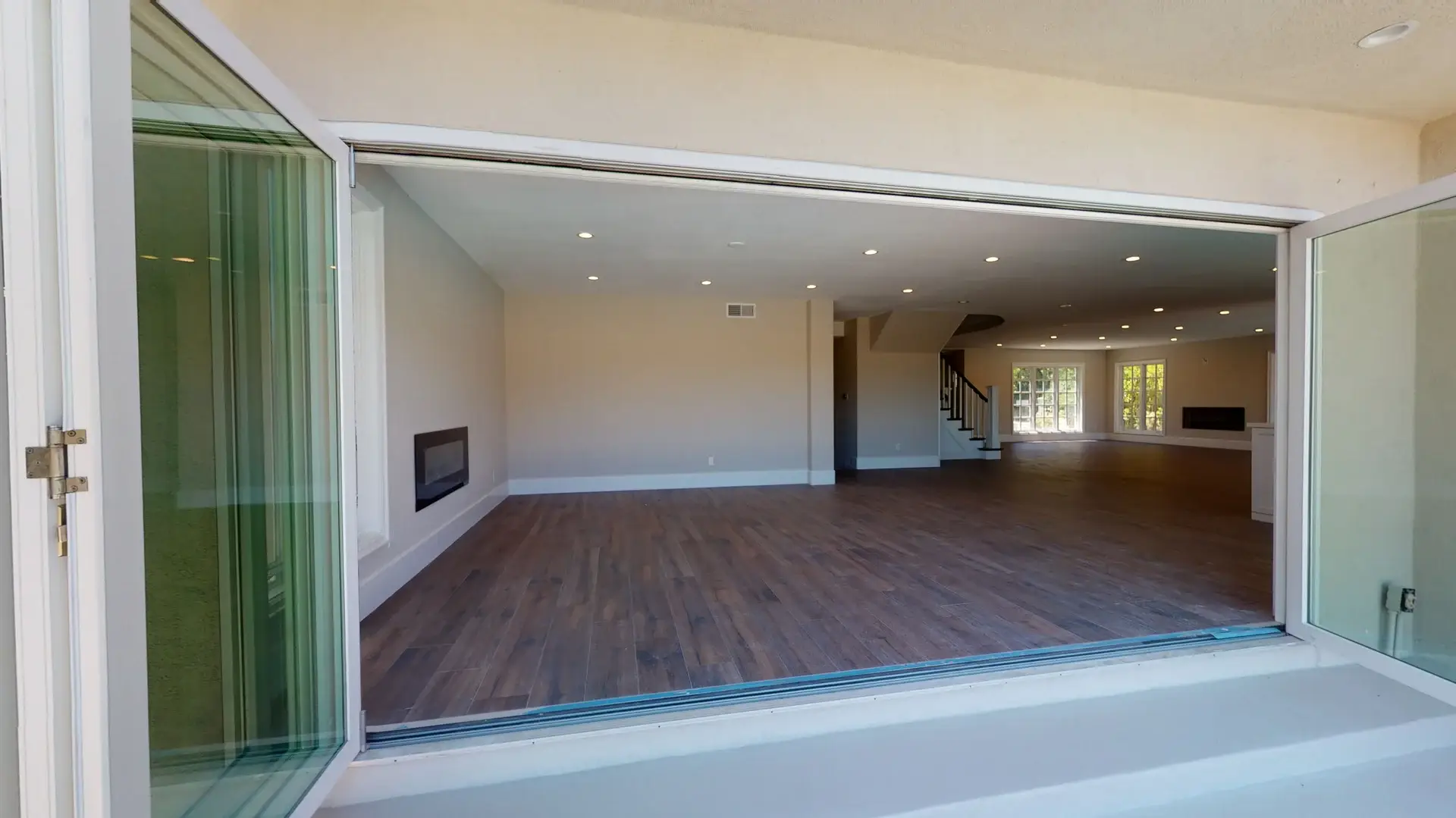 Open concept living room with recessed lighting and folding glass doors opening to the backyard