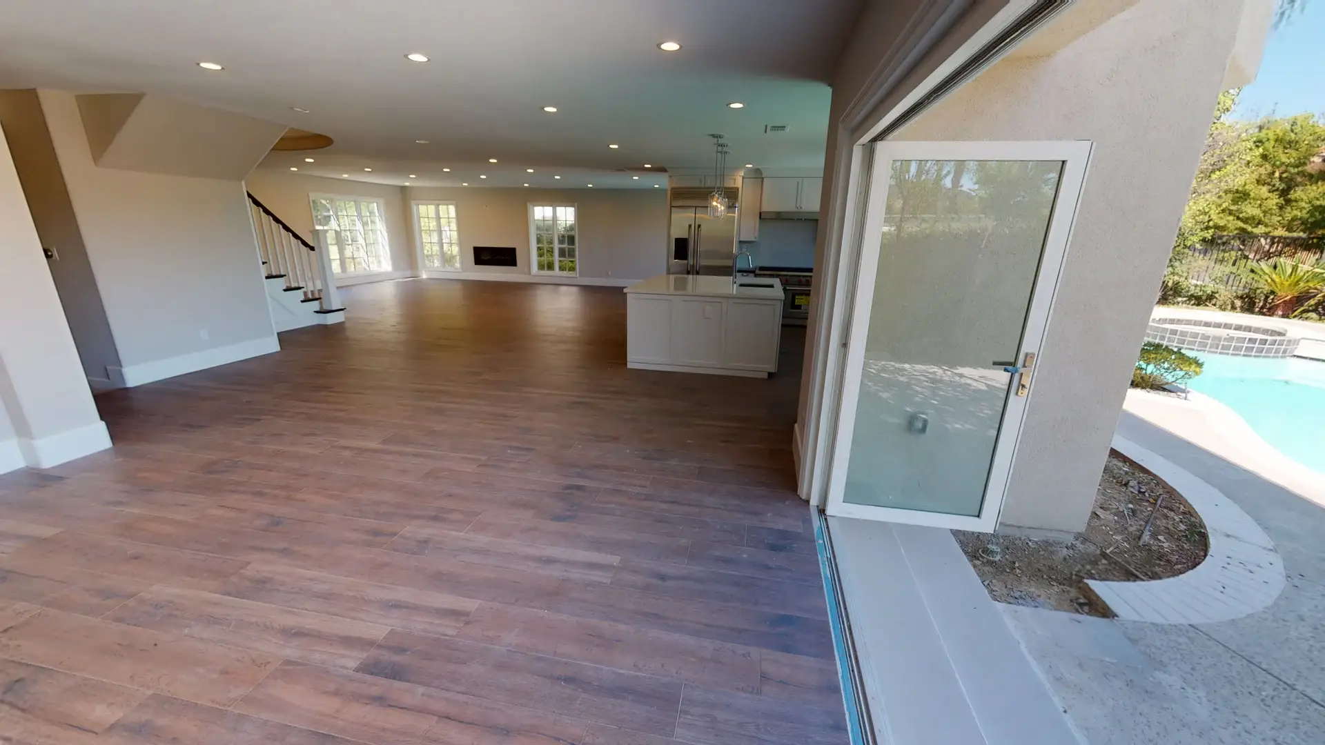 Open concept interior with a kitchen island and sliding glass doors to the backyard pool area