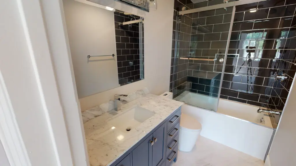 Home remodeling contractor completing a bathroom remodel in Orange County, featuring modern finishes, custom vanity, and a glass-enclosed tub.