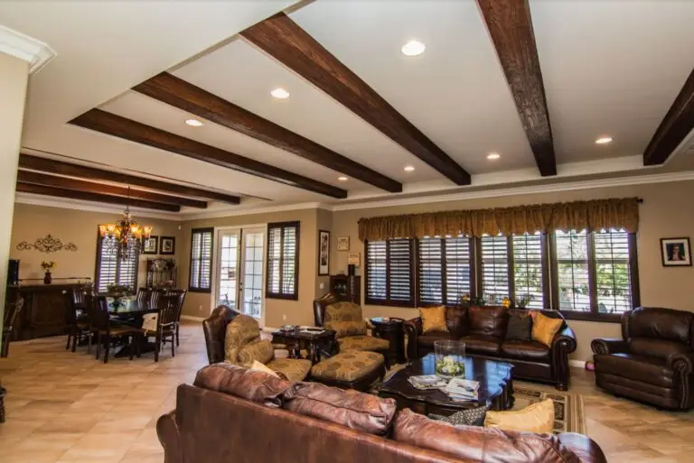 Spacious room addition featuring dark wood ceiling beams, recessed lighting, and a seamless open layout connecting the living and dining areas.