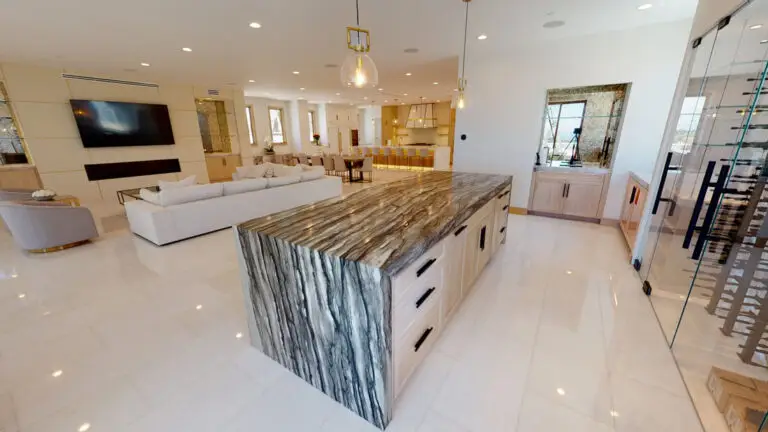 Elegant open concept room addition showcasing a striking stone kitchen island, modern pendant lighting, spacious living area, and built-in glass wine display.