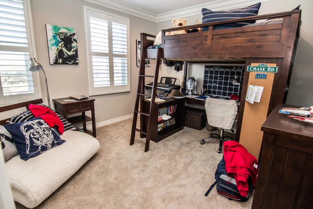 Stylish room addition showcasing a custom kid’s bedroom with a dark wood loft bed, built-in desk, Star Wars décor, and efficient use of space for sleeping and studying.