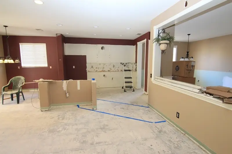 Kitchen remodeling in progress with partial demolition, exposed subfloor, removed cabinets, and marked layout areas for future kitchen island and cabinetry installation in an open floor plan layout.