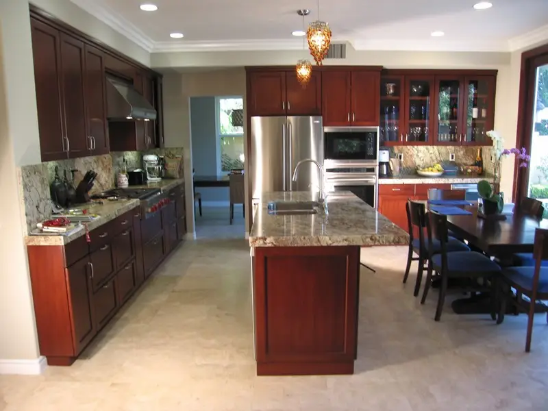 Complete kitchen renovation showcasing custom cherry wood cabinets, granite countertops, a central island with built-in sink, stainless steel appliances, and integrated dining space—perfect for modern family living.