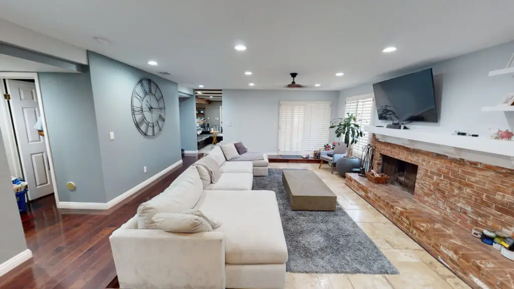 Completed living room renovation in Orange County with enclosed ceiling, recessed lights, soft gray tones, and updated entertainment area after loft conversion
