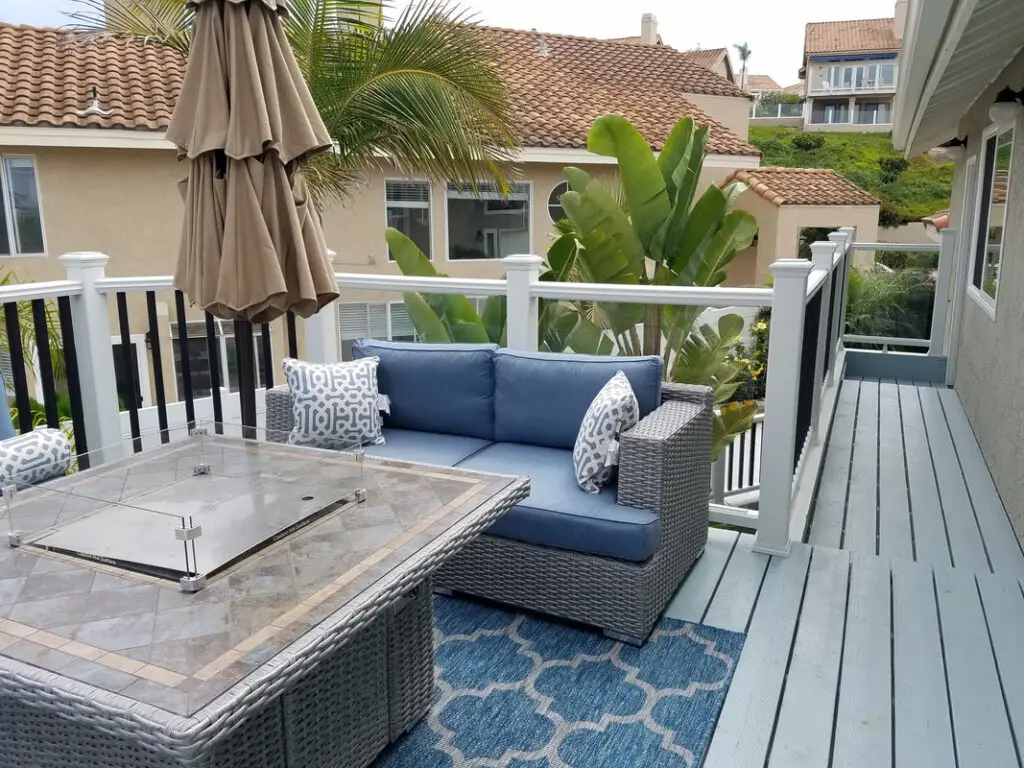Elevated coastal deck with composite flooring, modern railing, and a fire table surrounded by outdoor wicker seating