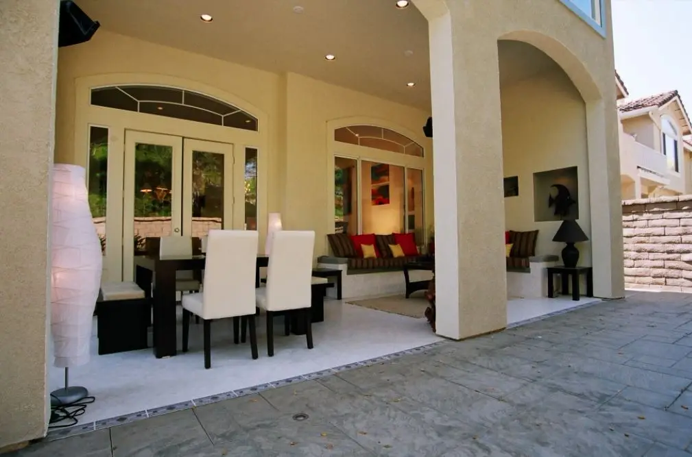 California room with covered outdoor dining area and built-in lounge seating, featuring arched openings and elegant finishes in an Orange County home