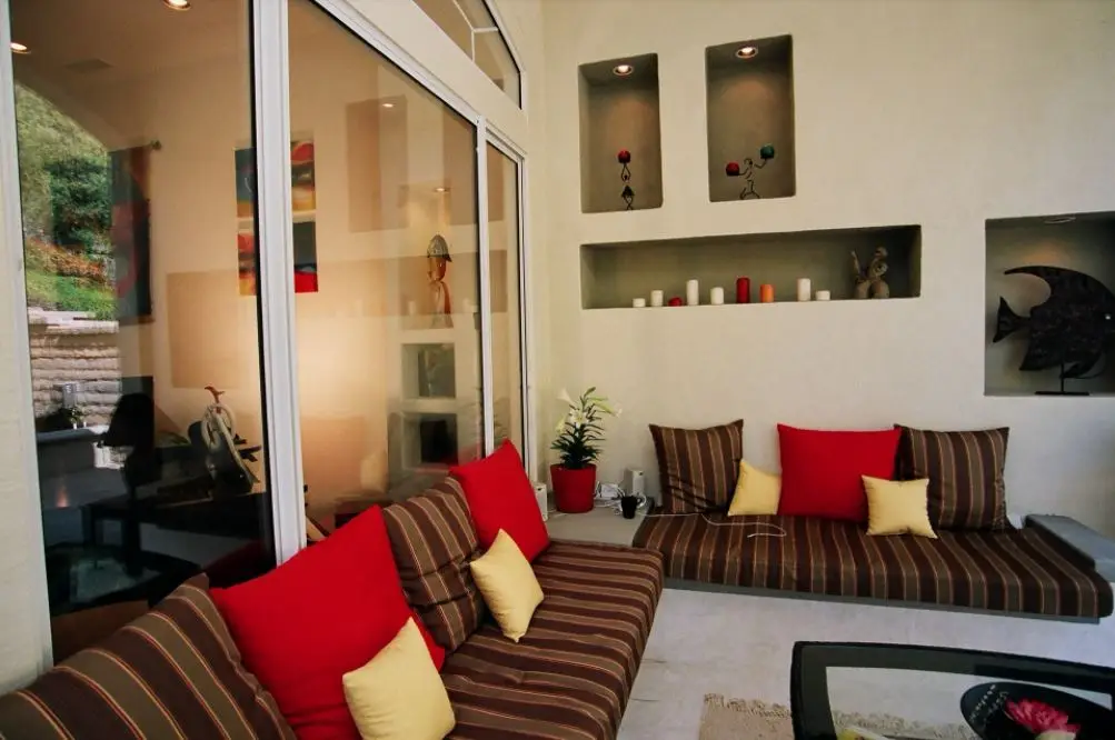 Custom California room with built-in bench seating, accent cushions, and decorative wall niches designed for stylish indoor-outdoor comfort in Orange County