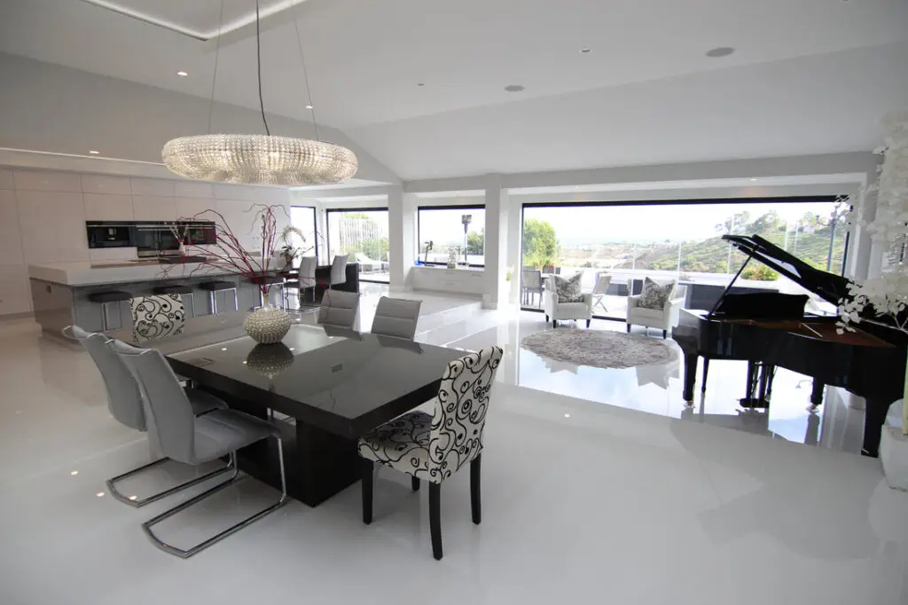 Modern open-concept living space created by a high ceiling conversion contractor, showcasing a bright kitchen, dining area, and expansive high ceilings.