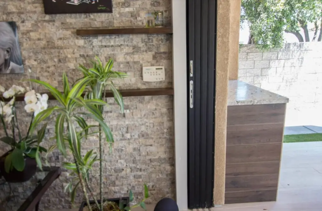 Close-up view of folding exterior patio doors connecting a modern indoor living space to a backyard, showcasing seamless indoor-outdoor transition.